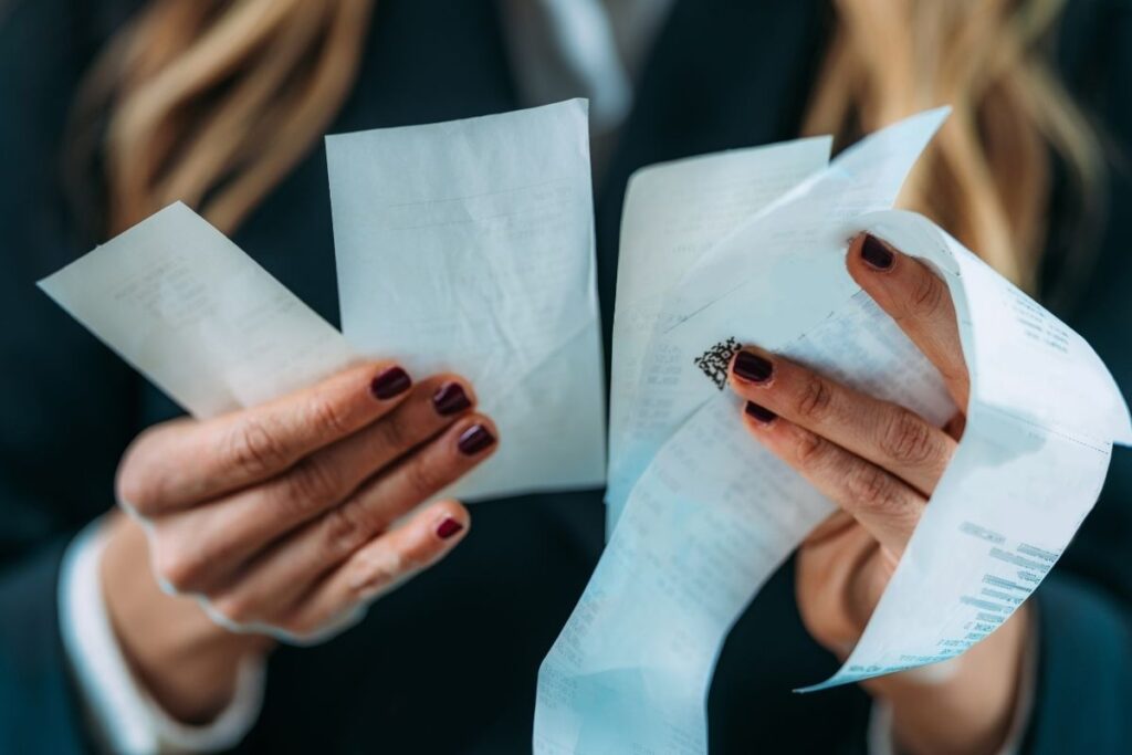 Woman holding multiple receipts showing daily expenses and cost of living in Dubai
