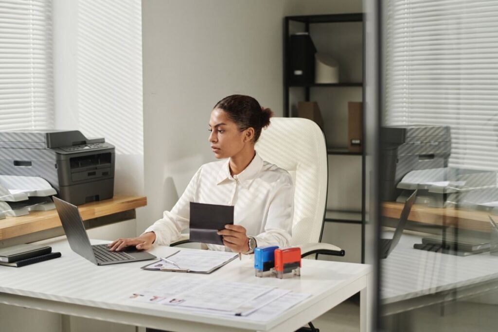 Frau bereitet Dokumente und Reisepass für das Auswandern nach Dubai am Laptop vor