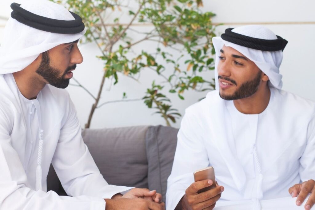 Zwei Männer in Emirati Kleidung sitzen im Gespräch. Symbolbild für Beratung zum Dubai Investorenvisum.