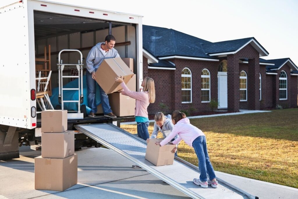 Family carrying moving boxes from truck while relocating to Dubai