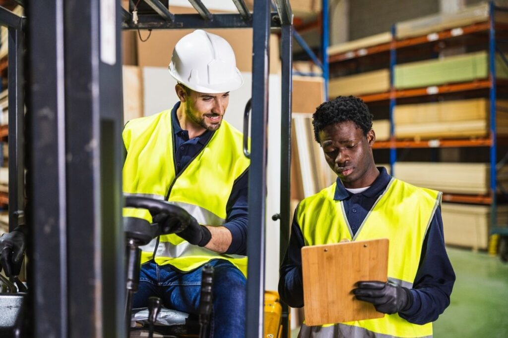 Zwei Lagerarbeiter mit Schutzkleidung arbeiten in Logistikhalle in Dubai mit Arbeitsvisum Dubai