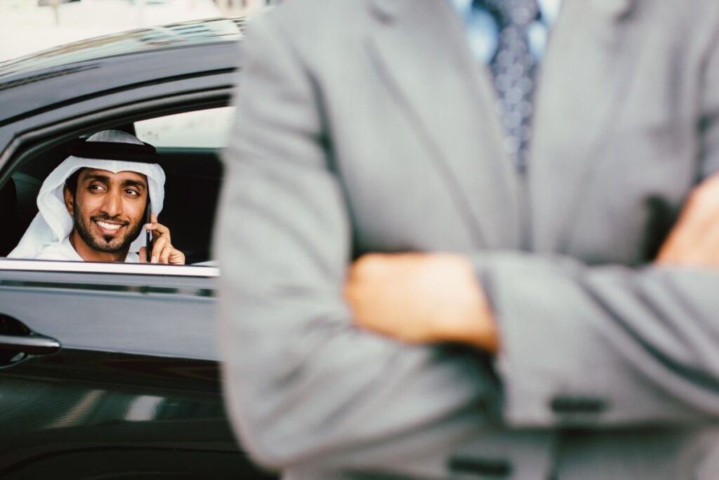 Mann in traditioneller Kleidung telefoniert im Auto während Geschäftsreise in Dubai mit Dubai Visa