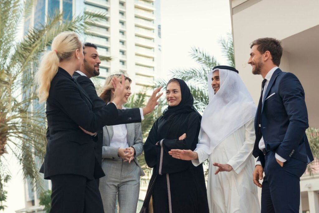 Internationale Geschäftsgruppe spricht vor modernen Gebäuden in Dubai. Symbolbild für Networking und Business-Chancen.