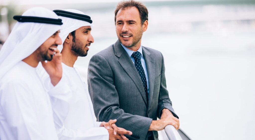 Geschäftsmann spricht mit zwei Männern in Emirati Kleidung. Symbolbild für Beratung zum Dubai Investorenvisum.