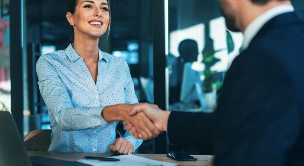 Geschäftsfrau begrüßt Geschäftspartner im Büro im Kontext Green Visa Dubai.