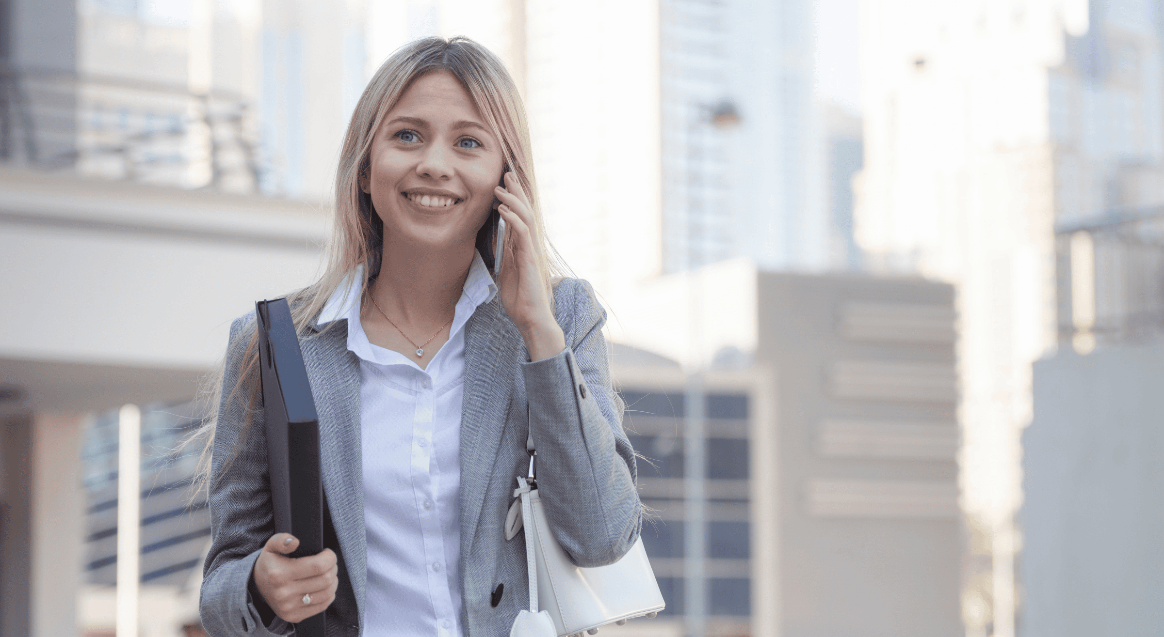 Geschäftsfrau beim Arbeiten in Dubai mit Smartphone und Aktenordner im modernen Geschäftsviertel